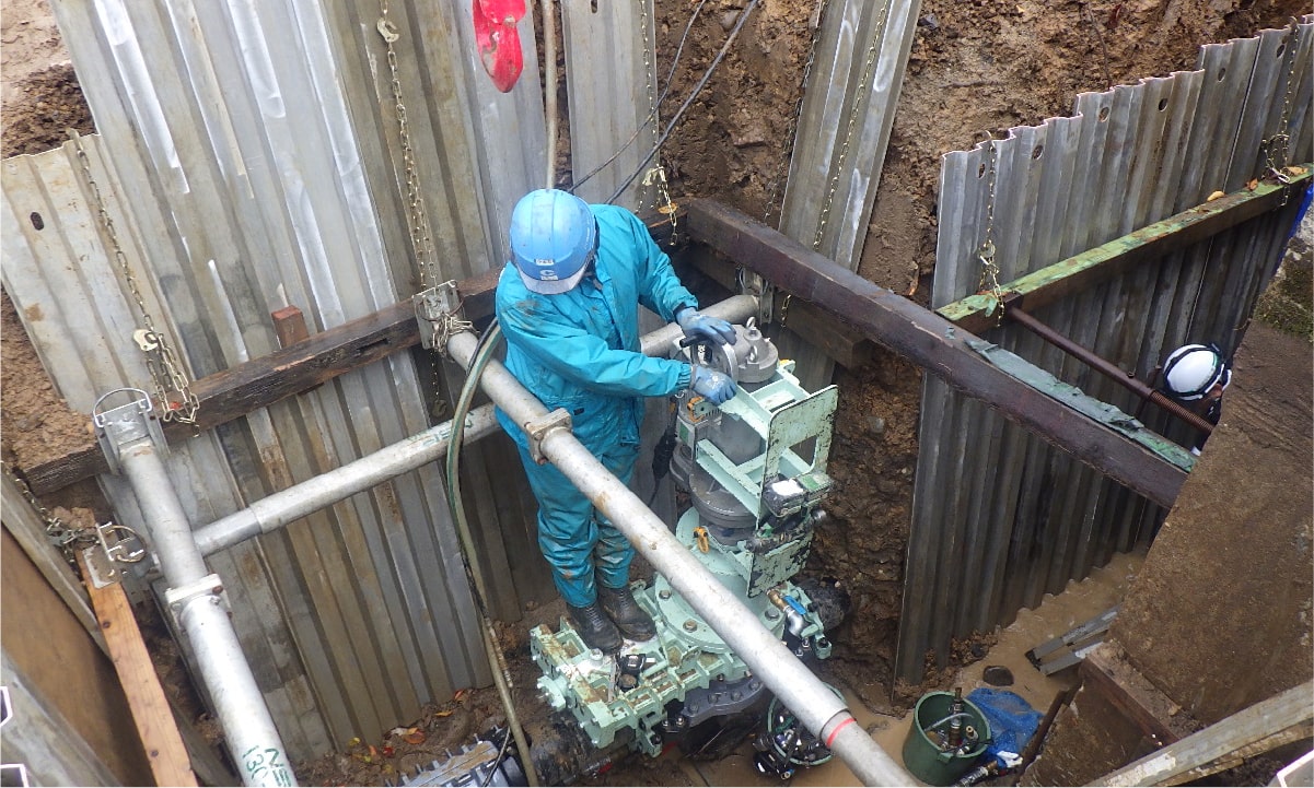 スタッフが特殊機械を使って水道工事 をする様子